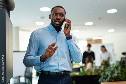 Stressed businessman having intense phone call in office