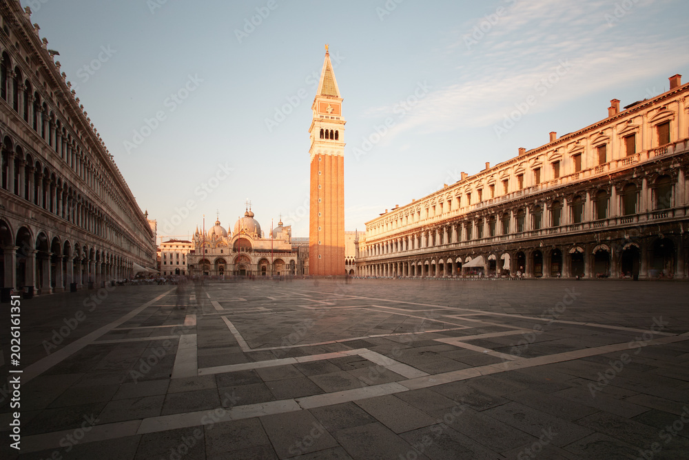 Naklejka premium Empty Saint Mark Square with the Campanile and Basilica in soft morning light in Venice, Italy. Colors: beige, blue, brown.