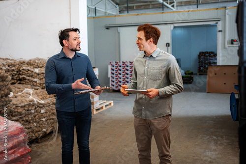 Foto Business partners discussing inventory in a productive warehouse