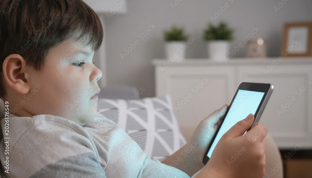Fototapeta premium Overweight child using smartphone during sedentary screen time lifestyle