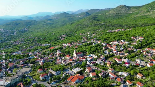 A charming Croatian Hreljin village nestled amidst lush green hills under a clear sky. Capturing the serene beauty of the Kvarner region's inland landscape.