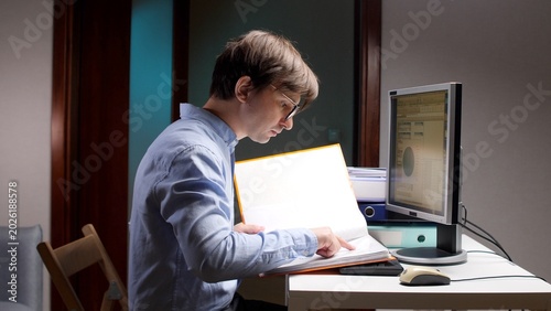 Cuadro en lienzo Man focusing on his work, sitting at a desk in a dimly lit home office, carefull