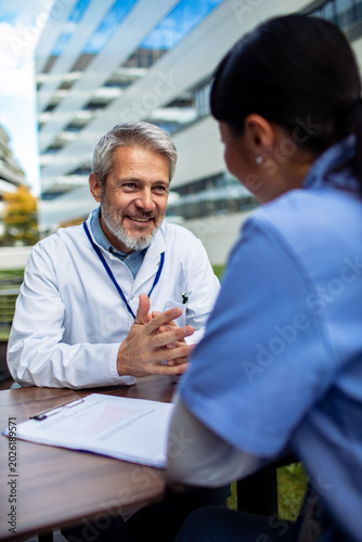 Senior doctor mentoring nurse during outdoor hospital meeting