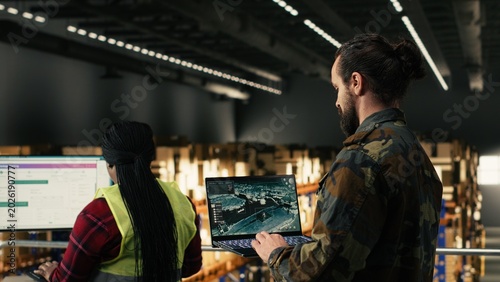 Obraz na plátně Military personnel using advanced military surveillance interface in warehouse, aerial footage monitoring for threat detection