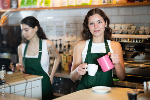 Canvas Print In back room of coffee shop, girl worker pours coffee into cups
