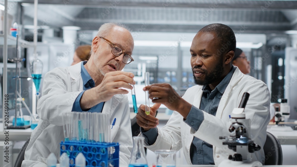 Fototapeta premium Teamworking molecular biologists in lab evaluate blue compound solution for new drug formulation. Laboratory coworkers testing experimental medication properties in vial, camera B