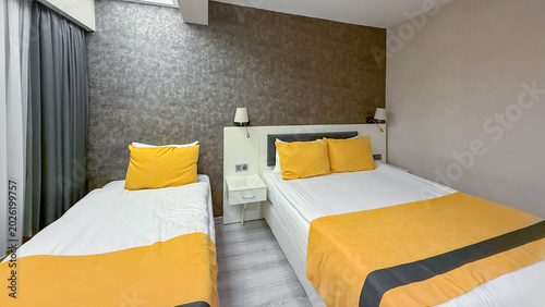 Foto Modern hotel bedroom interior with double bed single bed yellow pillows blankets
