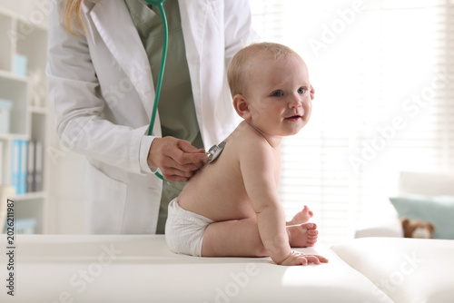 Tableau sur toile Pediatrician examining cute baby with stethoscope in hospital, closeup