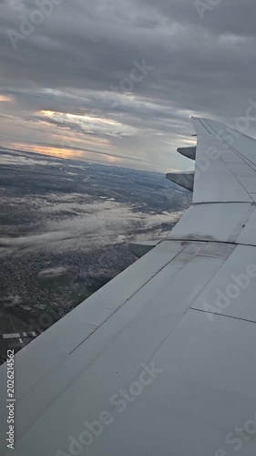 Vertical video of an airplane wing above the clouds at dawn on a flight to Buenos Aires. A view of Buenos Aires early in the morning at sunrise.
