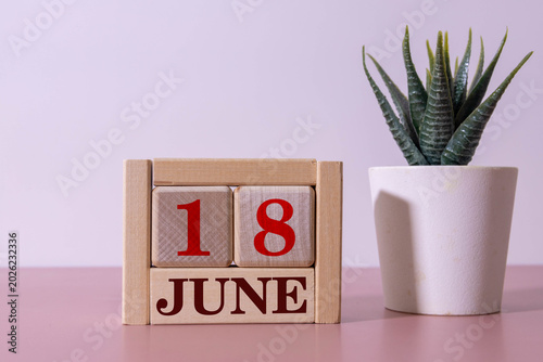 June 18. Wooden calendar made of blocks and a bouquet of lilacs