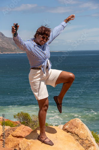 Koel Bay Western Cape South Africa. 14.02.2026.  Female holidaymaker jumping for joy, jumping,   with a view of Kogel Bay a scenic coastal background in the Western Cape South Africa.