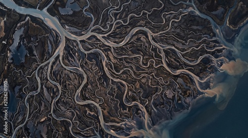 Aerial view of a braided river delta with intricate waterways and dark landforms