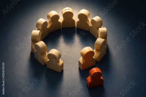 Wooden figures in circle with one isolated figure representing teamwork inclusion exclusion and group dynamics