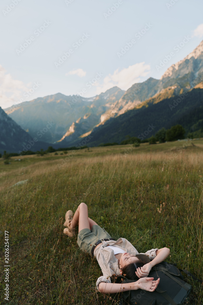 Fototapeta premium Woman lifestyle outdoor relaxation nature mountains meadow sunlight carefree scenery, casual clothing, serene moment, bright colors in a natural setting