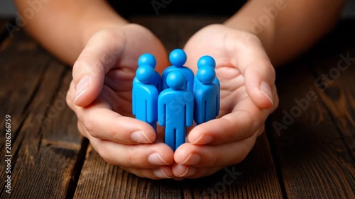Hands cradling small blue figures.