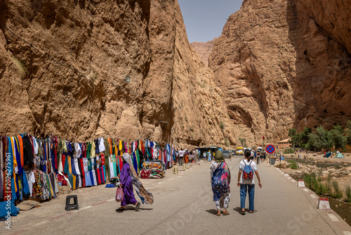 Tourists and traditional clothing stalls along the road inside Todra Gorge, Morocco.