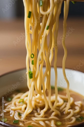 Chopsticks slowly lifting steaming noodles from the bowl, gentle swaying motion, steam rising from the hot broth, shallow depth of field