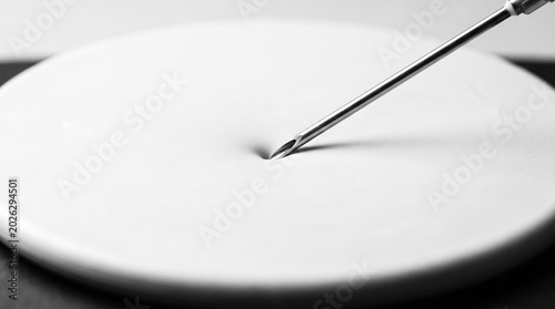 Metal Needle Touching White Round Plate Surface