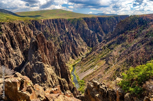 Scenic view of the Black Canyon of the Gunnison National Park in Colorado. The Gunnison River flows at the bottom of the deep, steep-walled canyon under a cloudy sky