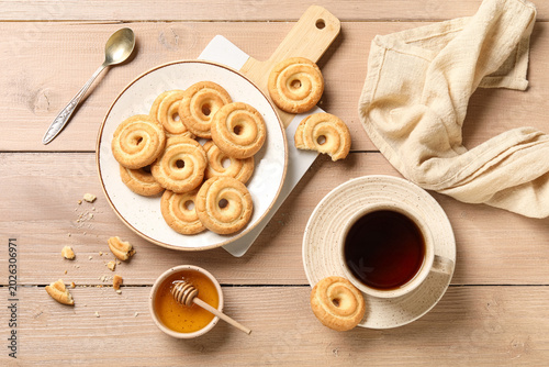 Valokuva Plate with tasty spritz biscuits and cup of tea on beige wooden background