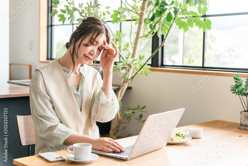 Vászonkép A young Asian woman struggling to work remotely while eating at a cafe