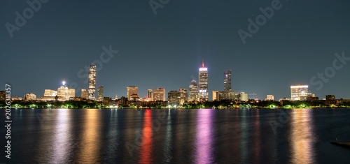 Картината върху платно Boston, United States, glows across the Charles River on a clear night, its towers casting colorful reflections onto calm water when seen from Cambridge's esplanade