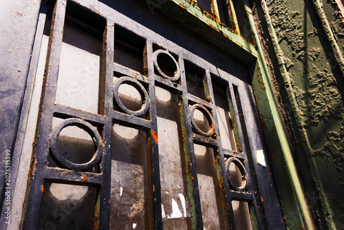 Fotografi Close-up of a rustic, old metal gate with a melancholic mood, showcasing industrial style and weathered texture