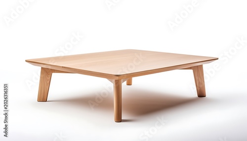 A wooden coffee table sits on a white floor in a modern living room with four legs and a square top made of light brown wood.