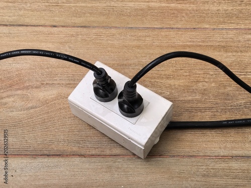 Two electrical plugs connected to a power strip on a wooden surface