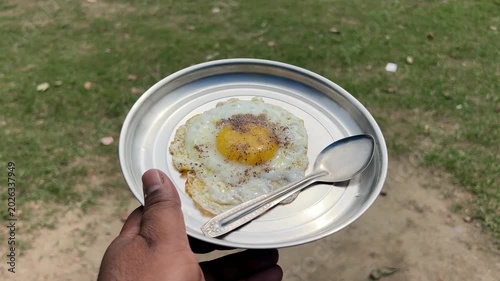 A perfectly prepared, warm poached egg served on a plate with an elegant outdoor garden terrace setting blurred beautifully in the background.