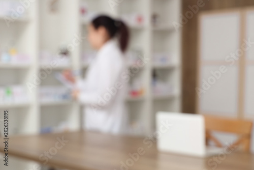 Blurred view of female pharmacist working at pharmacy