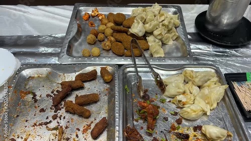 Leftover starters like fish fingers, momo, cheese balls, and chicken drumsticks served at an event in India