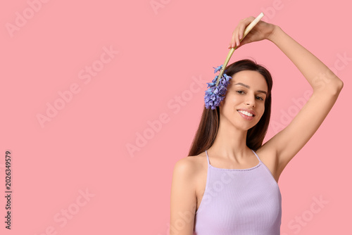 Happy smiling young woman holding hyacinth flower on pink background