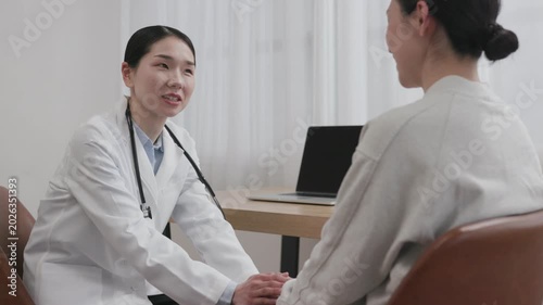 Asian Female Doctor Holding Patient Hand with Warm Smile to Encourage
