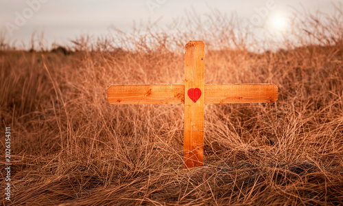 Fotografia A wood crucifix cross in a brown field with a red heart in the center