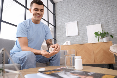 Young man taking pills from...