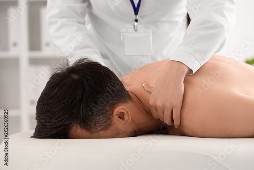 Female physiotherapist working with young man on couch in rehabilitation cent...