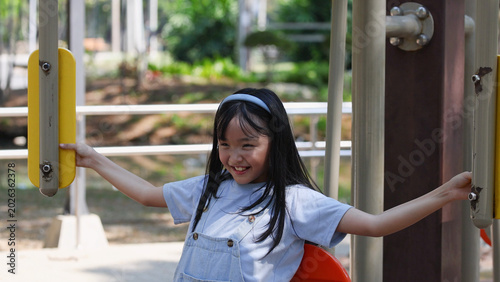Slika na platnu Smiling Young Thai Girl Using Outdoor Exercise Equipment in Lumpini Park