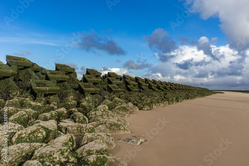 Φωτογραφία Algae-covered concrete sea defence blocks extend along New Brighton beach under