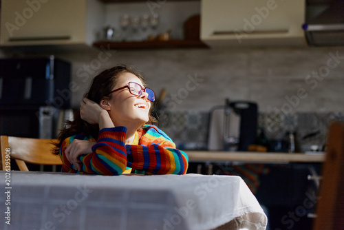 Quadro su tela Cheerful girl indoors, smiling with glasses, striped sweater, relaxed moment at