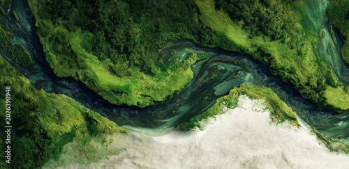 Aerial View of Verdant Landscape: A stunning aerial perspective reveals a winding river carving through a vibrant green landscape, with textured landmasses creating an abstract, organic pattern.