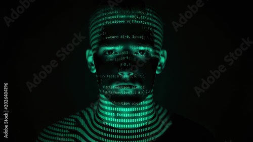 Dark portrait of person with turquoise code projected on their face, creating hacker-inspired glow
