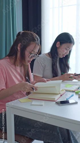 Two Asian girls doing homework together in living room
