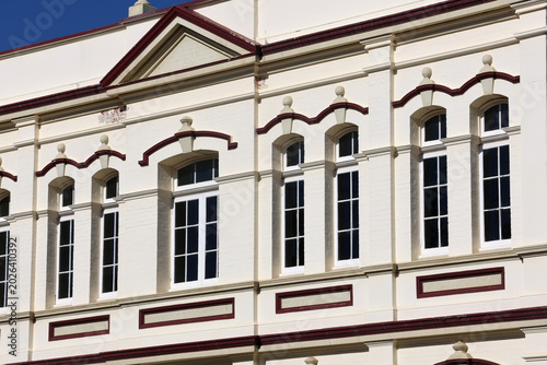 Architectural close-up of a historic building facade featuring elegant classical windows, ornate decorative trim, and traditional white plaster walls