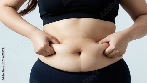 Woman's Belly Fat: Close-up of a woman pinching her soft belly, highlighting excess fat and the desire for a slimmer physique.