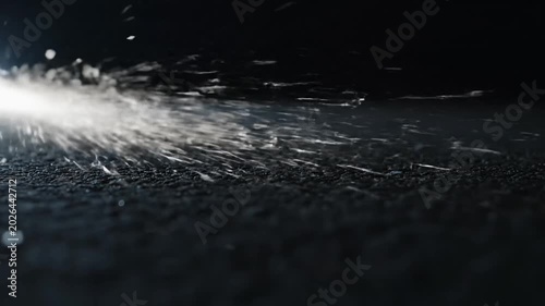 Bright metal sparks flying across dark textured ground surface.