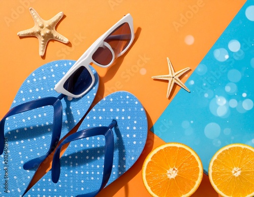 Summer vacation accessories with flip flops sunglasses starfish and oranges on orange background