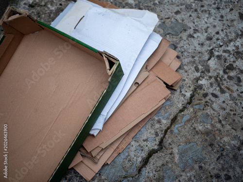 Stack of flattened cardboard boxes and paper waste prepared for recycling outdoors. Used packaging materials on concrete surface with eco recycling and waste management concept.
