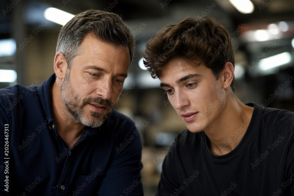 Fototapeta premium Experienced Technician Mentoring Young Apprentice in Industrial Workshop 