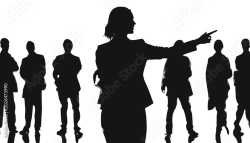 Businesswoman stands in front of a group of colleagues while pointing her finger toward a distant direction to show the team the correct path they must take to achieve their shared corporate goals.